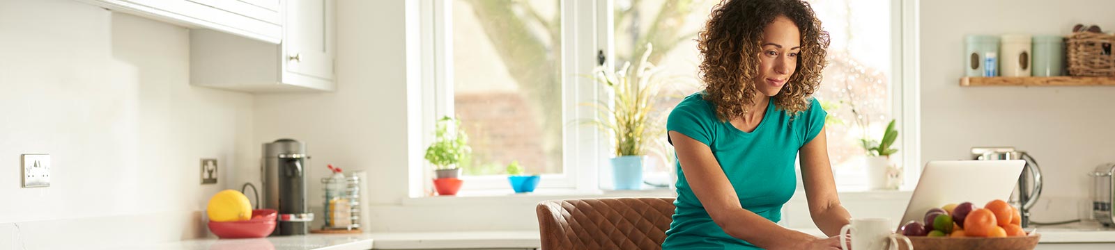 Woman using laptop in kitchen at home.